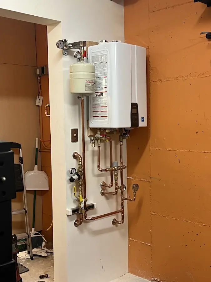 Plumbing technician inspecting water heater connections in Three Lakes